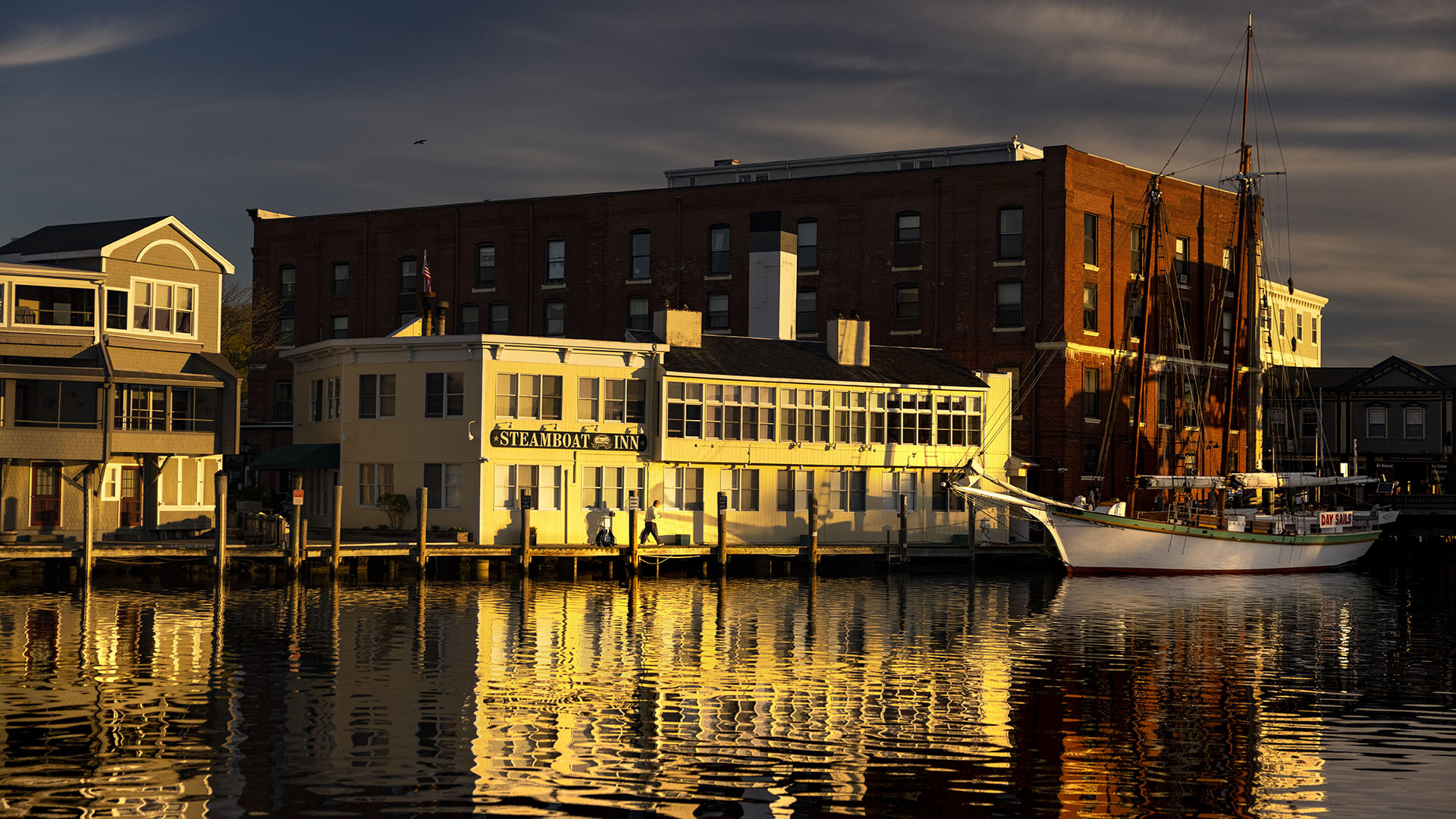 The Steamboat Inn and the sailboat Argia light up during the sunrise over the Mystic River.